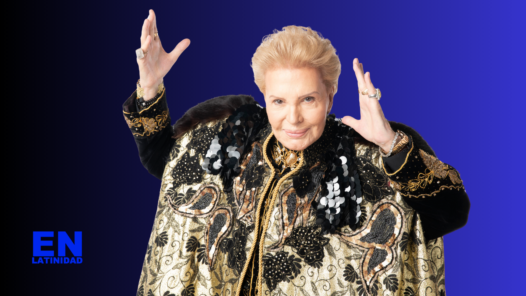 Walter Mercado dressed in a flowing gold and red cape, smiling warmly during a television appearance, symbolizing his iconic presence and lasting influence on Latino spirituality and pop culture.