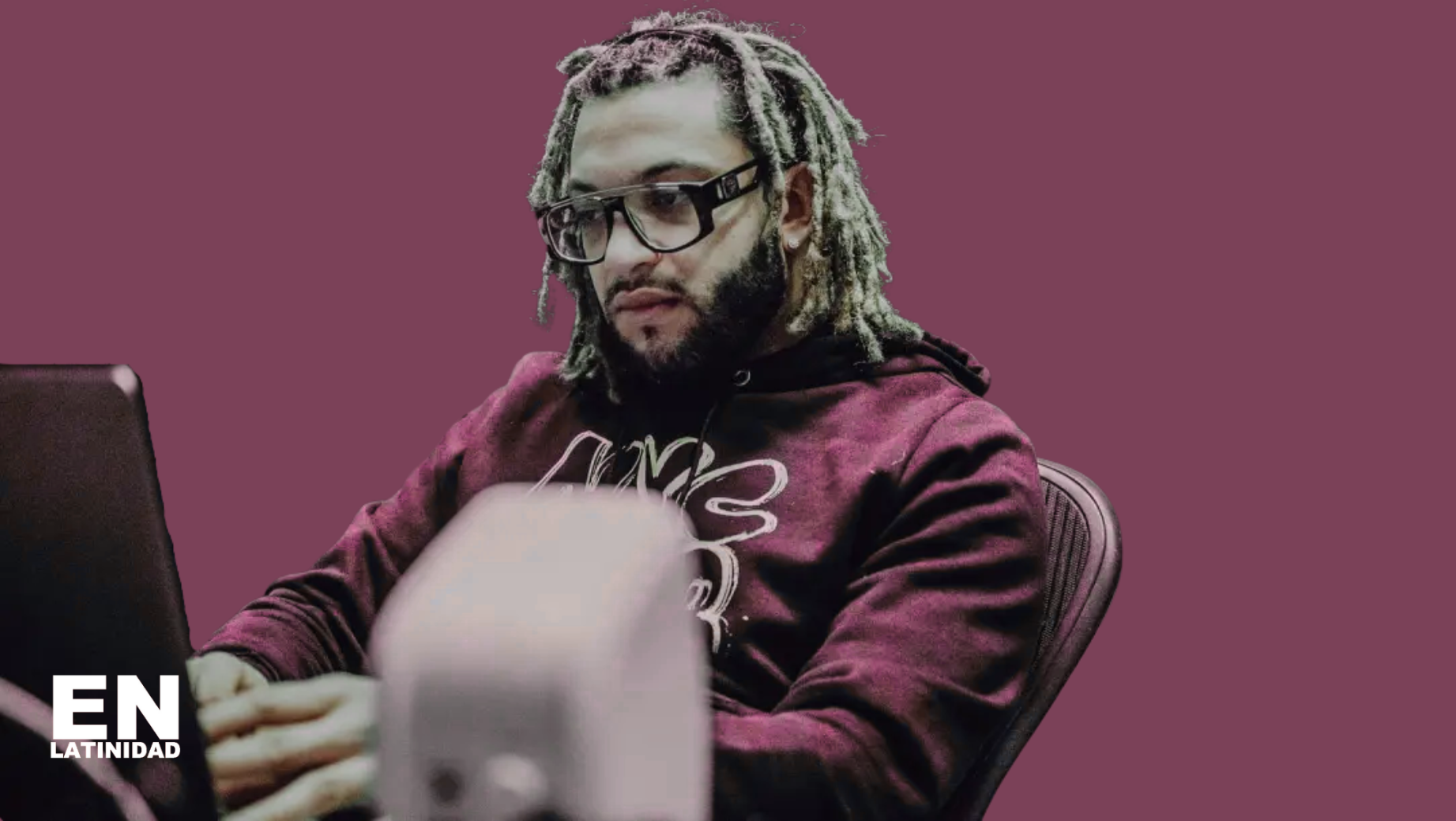 Dominican music producer Xtassys in the studio, wearing headphones and focused on mixing tracks, capturing the creative energy behind reggaeton hits.